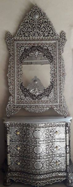 an ornate silver dresser with mirror above it