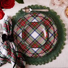 a table setting with plates, silverware and red roses on the tablecloths