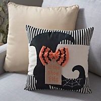 a gray couch with a black and white striped pillow on it, decorated with an orange bow