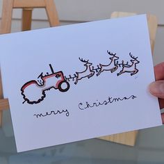 a hand holding up a christmas card with santa's sleigh