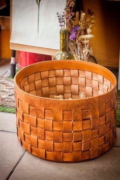 a basket sitting on the ground next to a vase with flowers in it and some grass