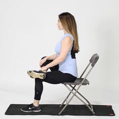 a woman sitting on a chair with her legs crossed and holding a black object in front of her