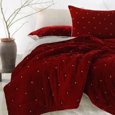 a bed covered in red velvet with white stars on the comforter and pillow cases