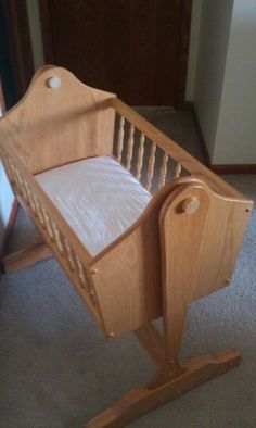 a baby crib made out of wood with white sheets on the top and bottom