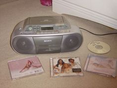 the cd player is sitting on the floor next to other cds and dvd's