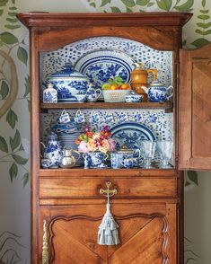 an old china cabinet with blue and white dishes on it