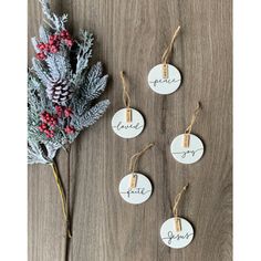 four white tags with the word love are hanging on a wooden table next to a flower