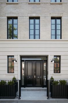 the front entrance to an apartment building with two black planters on either side of the door