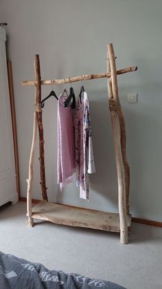 a bed room with a wooden frame and clothes hanging on the rack next to it