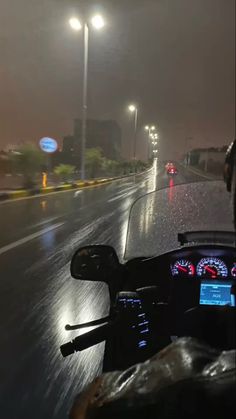 a motorcycle driving down a rain soaked street at night