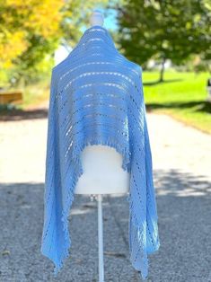 a blue knitted shawl sitting on top of a white mannequin