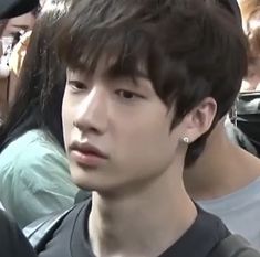 a young man with ear piercings standing in front of a group of people