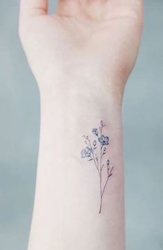 a small blue flower tattoo on the wrist