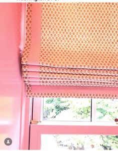 a window with pink and orange roman blinds