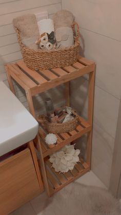 a wooden shelf with baskets and towels on it in a bathroom next to a sink