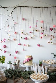 a table topped with cakes and desserts covered in pink flowers hanging from the ceiling