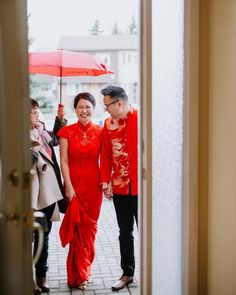 a man and woman in red are holding an umbrella