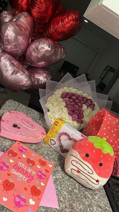 valentine's day decorations and greeting cards are on the counter in front of balloons