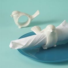 two white birds sitting on top of a blue plate next to a napkin dispenser