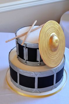 there is a cake that looks like a drum set on top of the cake, with two sticks sticking out of it