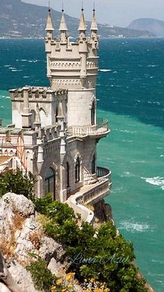 an old castle sitting on top of a cliff next to the ocean