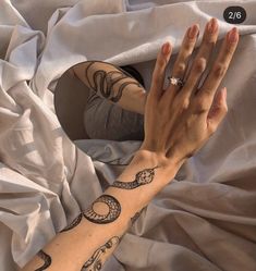 a woman's arm with tattoos on it and her hand resting on the bed