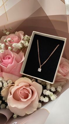 pink roses and white baby's breath in a box with a necklace on it