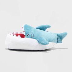 a stuffed shark is laying on top of a white slipper with its mouth open