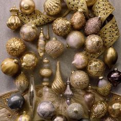 an assortment of christmas ornaments are arranged on a table top with gold trimmings