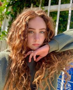 a woman with long curly hair posing for the camera