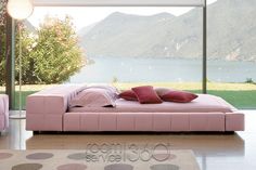 a pink bed sitting in the middle of a living room next to a large window