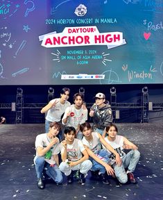 a group of young men posing for a photo in front of a screen with writing on it