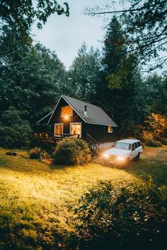 a car is parked in front of a small cabin at night with the lights on