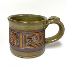 a brown and green coffee cup sitting on top of a white table