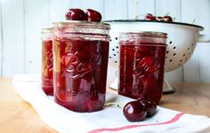 two jars filled with cherries sitting on top of a table