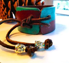 "Woman's repurposed leather belt cuff bracelet with a smooth design. The bracelet is 1 1/2\" wide and 6 1/2\" long. It is hand painted with permanent leather paint and sealed with a clear coat. The fastener is a leather strap  style with two (2) filigree high polished beads of silver color. This bracelet is adjustable to accommodate a wrist measuring approximate 6 1/2\" to 8\". #cuff 8" Unique Brown Cuff Bracelet, Adjustable Brown Leather Bracelet With Patina, Adjustable Brown Cuff Bracelet With Patina, Festival Brown Cuff Bracelet With Patina, Unique Adjustable Hand Painted Cuff Bracelet, Rectangular Brown Cuff Bracelet Gift, Leather Cuff Bracelets, Recycled Bracelets, Leather Paint