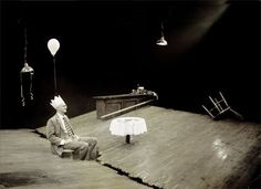 a man sitting on top of a wooden floor next to a table with a white cloth