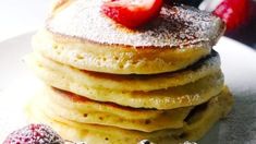 a stack of pancakes with powdered sugar and strawberries on the top are ready to be eaten