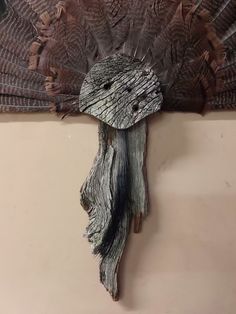 a decorative piece of wood that looks like a bird's head hanging on a wall