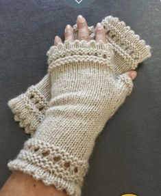 a woman's hand wearing a pair of knitted fingerless gloves