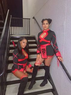 two women dressed in red and black posing on stairs