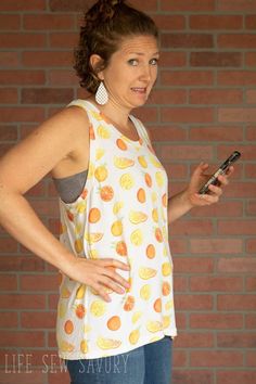 a woman standing in front of a brick wall holding a cell phone