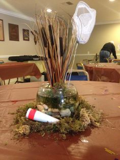 a vase filled with plants and rocks sitting on top of a table covered in dirt