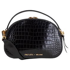 100% authentic Prada Odette Crocodile Bandoliera shoulder bag in black croco leather. Its dual zip compartments are lined with smooth black lambskin and equipped with one slip pocket. Comes with a detachable, adjustable shoulder strap and a top handle. The bag features gold-tone hardware. Has been carried and is in excellent condition. Measurements Height 14cm (5.5in) Width 20.5cm (8in) Depth 6.5cm (2.5in) Shoulder Strap Length 130cm (50.7in) Hardware Gold-Tone All our listings include only the listed item unless otherwise specified in the description above. Luxury Evening Bag With Crocodile Pattern, Designer Crocodile Pattern Shoulder Bag For Evening, Evening Crocodile Pattern Top Handle Shoulder Bag, Formal Crossbody Shoulder Bag With Crocodile Pattern, Luxury Crossbody Bag With Crocodile Pattern, Evening Satchel Shoulder Bag With Crocodile Pattern, Luxury Crocodile Pattern Crossbody Bag, Designer Crossbody Bag With Crocodile Pattern, Evening Leather Bag With Crocodile Pattern