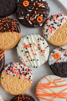 decorated cookies on a white plate with orange and black sprinkles in the middle