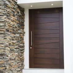 a modern wooden door in front of a stone wall