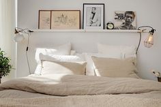 a bed with white linens and two pictures on the wall above it in a bedroom