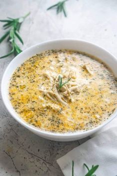 a white bowl filled with soup sitting on top of a table next to napkins