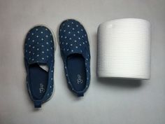 a pair of blue shoes next to a roll of toilet paper