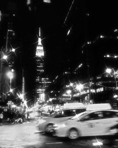 a black and white photo of cars driving down the street at night in new york city